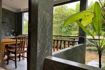 a dining room with a table and a balcony at Tann Anda Resort in Thalang