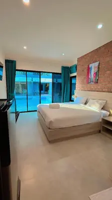 a bedroom with a large bed and a brick wall at Bests Village & Villa - Chalong Bay Phuket in Chalong