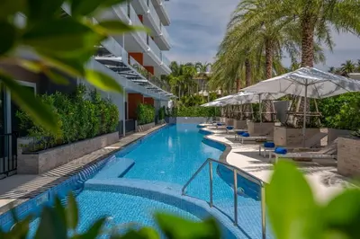 a swimming pool with chairs and umbrellas next to a building at Babylon Sky Garden in Rawai Beach