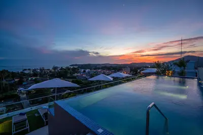 a swimming pool with a view of a city at dusk at Babylon Sky Garden in Rawai Beach