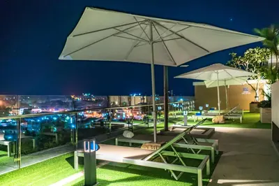 a patio with chairs and an umbrella at night at Babylon Sky Garden in Rawai Beach