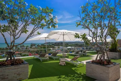 a patio with chairs and an umbrella on the grass at Babylon Sky Garden in Rawai Beach
