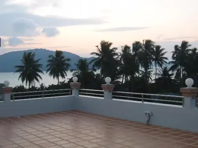 a balcony with a view of the ocean and palm trees at Raya Rawai Place in Rawai Beach
