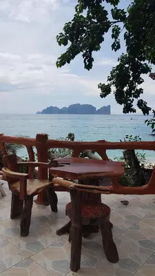 a wooden picnic table and bench next to the ocean at Paradise Pearl Bungalows in Phi Phi Don