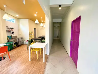 a room with a purple door and a table and chairs at Sleepy Station Hostel in Kata Beach