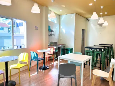 a restaurant with tables and chairs in a room at Sleepy Station Hostel in Kata Beach
