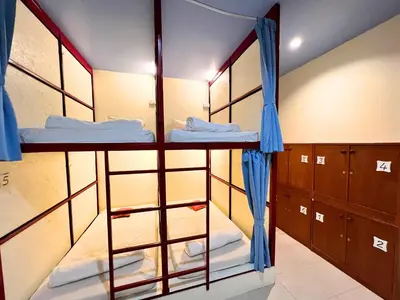 a room with three bunk beds with blue curtains at Sleepy Station Hostel in Kata Beach