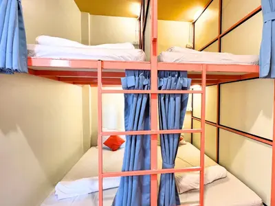 a room with two bunk beds with blue curtains at Sleepy Station Hostel in Kata Beach