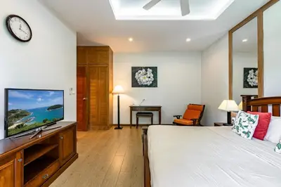 a bedroom with a bed and a flat screen tv at Champagne Villa Luxurious Tropical Pool Villa in Rawai Beach