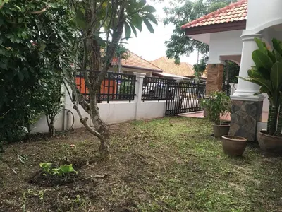 a yard with a fence and a tree in front of a house at Beautiful 3 Bedroom Garden Villa in Chalong