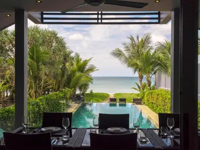 a dining room with a view of the ocean at Infinity Blue Phuket by Elite Havens in Natai Beach