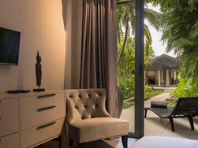 a living room with a chair and a dresser and a window at Infinity Blue Phuket by Elite Havens in Natai Beach