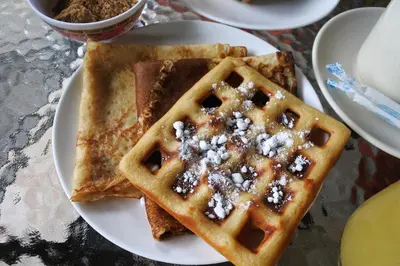 a plate of waffles with powdered sugar on it at Hi Karon Beach in Karon Beach