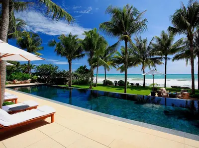 a swimming pool with palm trees and the ocean at Villa Nandana by Elite Havens in Natai Beach