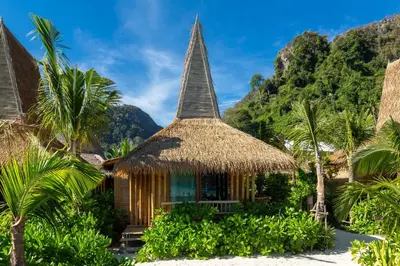 a resort with a thatched roof and palm trees at Phi Phi CoCo Beach Resort in Phi Phi Don