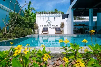 a swimming pool with two chairs next to a sign at The Seaton House in Rawai Beach