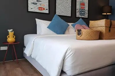 a bedroom with a white bed with blue pillows at The Seaton House in Rawai Beach