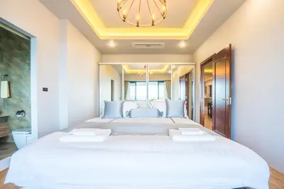a bedroom with a large white bed with a chandelier at Nakara Hill Phuket in Chalong