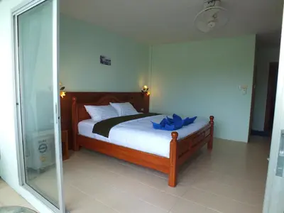 a bedroom with a bed with a glass door at saithong guesthouse in Rawai Beach