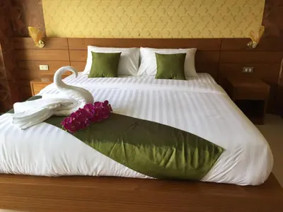 two swans on a bed with flowers on it at saithong guesthouse in Rawai Beach