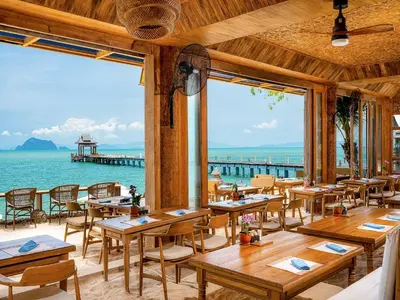 a restaurant with tables and a view of the ocean at Santhiya Koh Yao Yai Resort & Spa - Compulsory Join Santhiya Speedboat from-to Ao Po Grand Marina at Phuket in Ko Yao Yai
