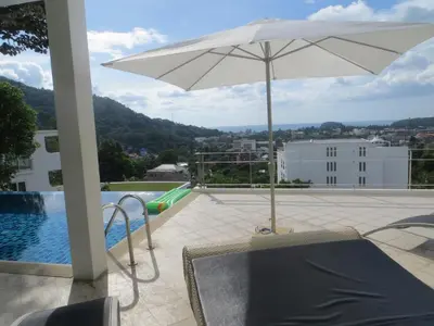 a patio with an umbrella and a swimming pool at Villa Ginborn amazing 5-Bedroom Sea-View Pool Villa 5 Minutes to Kata Beach in Kata Beach
