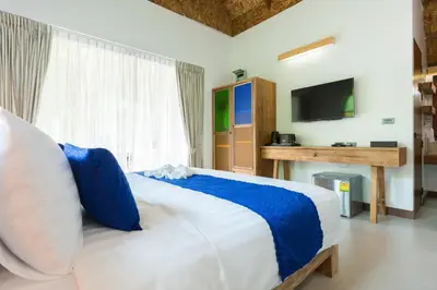 a bedroom with a large bed with a tv on the wall at Purana Resort Koh Yao Noi - SHA Extra plus in Ko Yao Noi