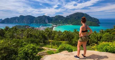 a woman standing on a rock looking at the ocean at Rehab Hostel in Phi Phi Don