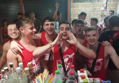 a group of men standing around a table with drinks at Rehab Hostel in Phi Phi Don