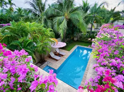a garden with a swimming pool and purple flowers at Perfect 2br Pool Villa In Residence Bangtao Beach4 in Bang Tao Beach