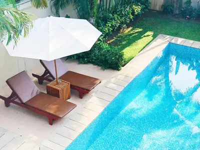 an umbrella and two chairs next to a swimming pool at Perfect 2br Pool Villa In Residence Bangtao Beach4 in Bang Tao Beach