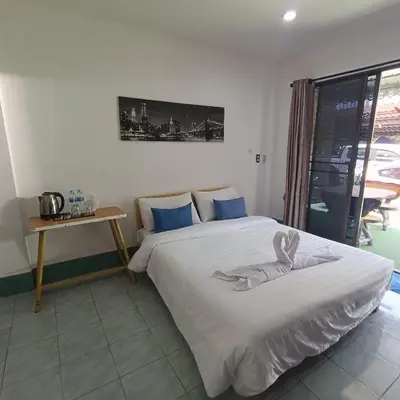 a bedroom with two beds and a table and a window at The Guest House - Apartment in Patong Beach