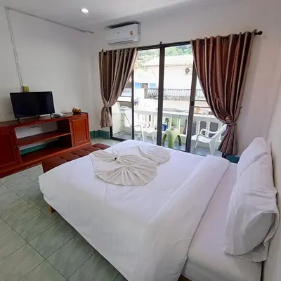 a bedroom with a large white bed and a television at The Guest House - Apartment in Patong Beach