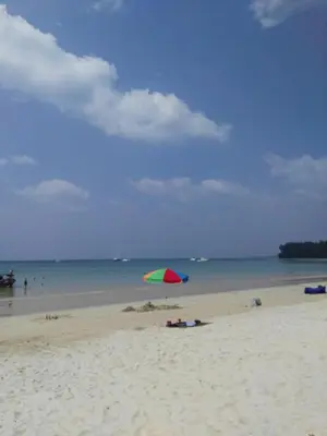a beach with a colorful umbrella on the sand at The Title Residencies Naiyang Pool View in Nai Yang Beach