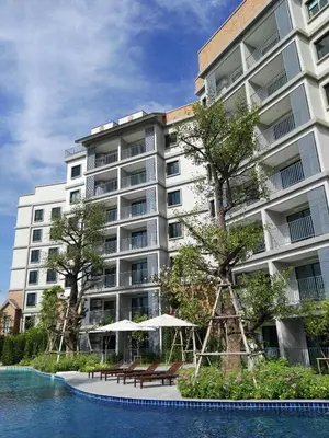 a large apartment building with tables and umbrellas next to a pool at The Title Residencies Naiyang Pool View in Nai Yang Beach