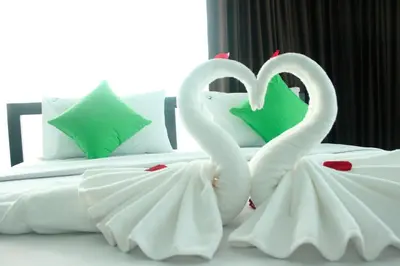 two white swans making a heart on a bed at The Aireen Hotel in Ao Nang Beach