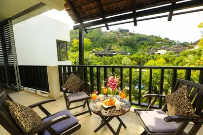 a balcony with chairs and a table with drinks on it at Bangtao Beach Garden by RESAVA in Bang Tao Beach