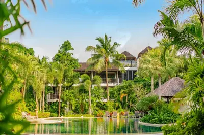 an exterior view of a resort with a pool and palm trees at Bangtao Beach Garden by RESAVA in Bang Tao Beach