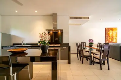 a kitchen and dining room with a table and chairs at Bangtao Beach Garden by RESAVA in Bang Tao Beach