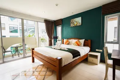 a bedroom with a bed with a green wall at OK Phuket in Kata Beach