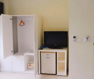 a living room with a television and a small refrigerator at OK Phuket in Kata Beach