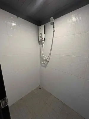 a bathroom with a shower in a white wall at Blanco Central in Phi Phi Don