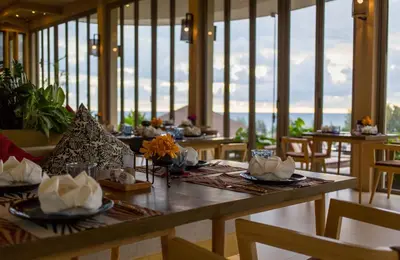 a dining room with tables and chairs and windows at Mandarava Resort and Spa, Karon Beach in Karon Beach