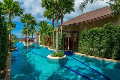 a swimming pool with blue water and palm trees at Mandarava Resort and Spa, Karon Beach in Karon Beach