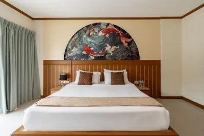 a bedroom with a large bed with a painting on the wall at The Eden Park in Patong Beach