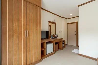 a room with wooden cabinets and a desk with a television at The Eden Park in Patong Beach