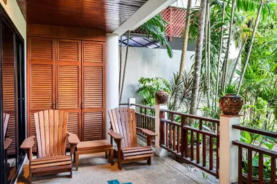 a balcony of a house with chairs and trees at The Sand Beach Apartment in Nai Harn Beach