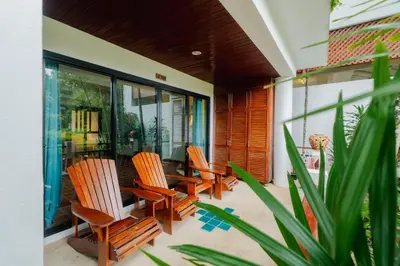 a patio with chairs and a table on a house at The Sand Beach Apartment in Nai Harn Beach