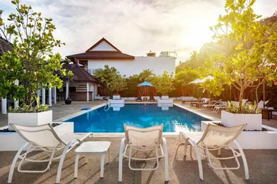 a pool at a hotel with chairs and tables at The Sand Beach Apartment in Nai Harn Beach