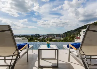 a balcony with chairs and a table and water at Villa Momo Private Pool near Kata Beach in Kata Beach